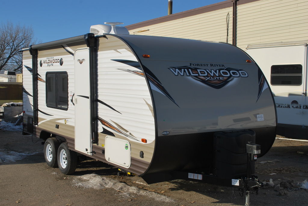 Beige Forest River Wildwood X-Lite travel trailer in an RV lot with melted snow surrounding it.
